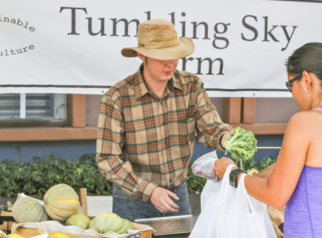 TYSON WEAVER, OF Tumbling Sky Farm in Washougal, packages vegetables for a customer at his Camas Farmers Market stand on Wed., Sept. 21.
