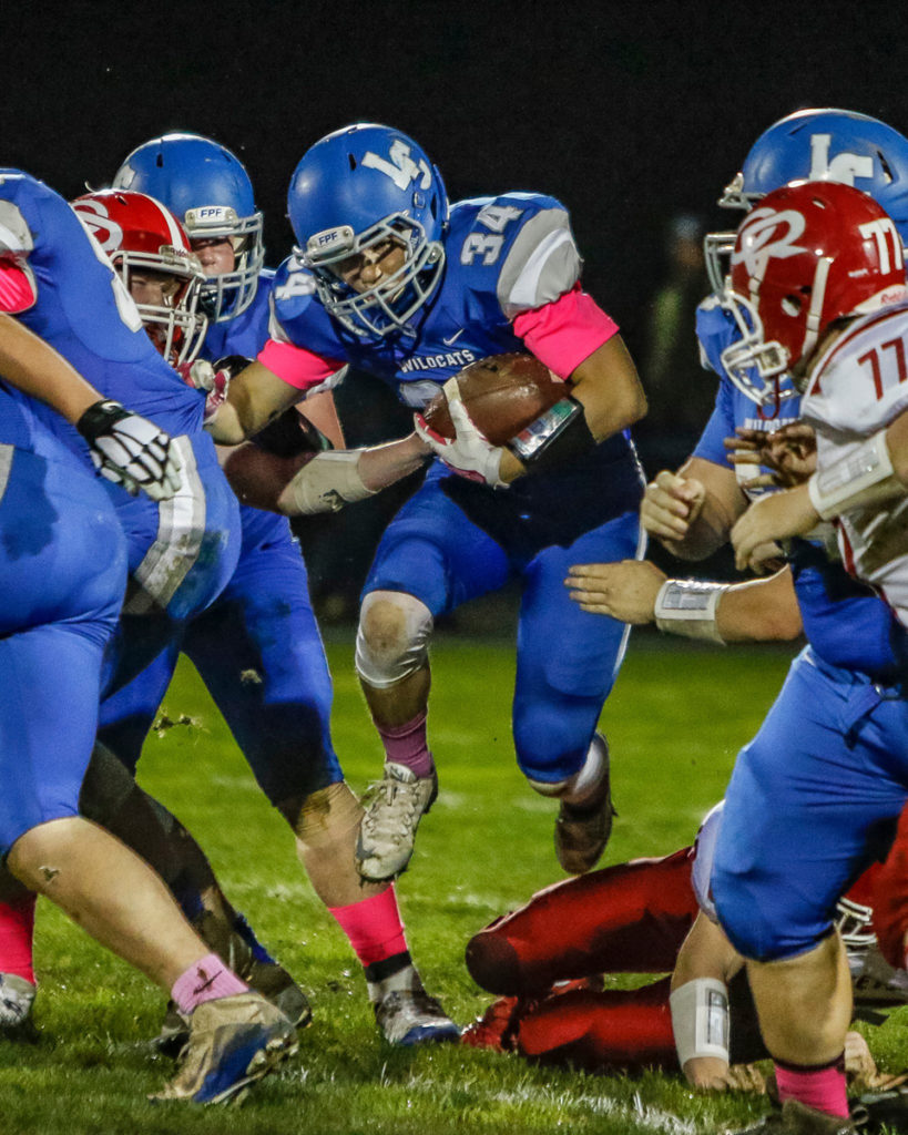 La Center running back Jeffrey Mayolo (34) jumps through an opening in the Castle Rock defense