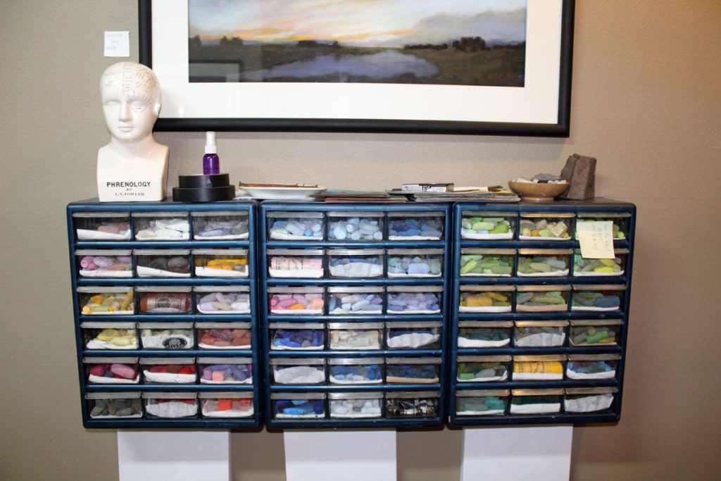 A case of handmade pastels sits under one of artist Susan Mitchell’s paintings at Mitchell’s art studio in east Vancouver.