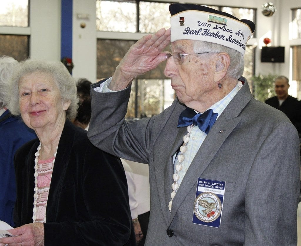 Local Pearl Harbor survivor, Ralph Laedtke, of Washougal, salutes during a Wed., Dec. 7, Pearl Harbor anniversary remembrance event at the 40 Et 8 Bingo Hall in north Vancouver. To his left is Joan Harshberger, of Woodland, widow of another local Pearl Harbor survivor, Earl W. Harshberger, Jr. Photo by Kelly Moyer