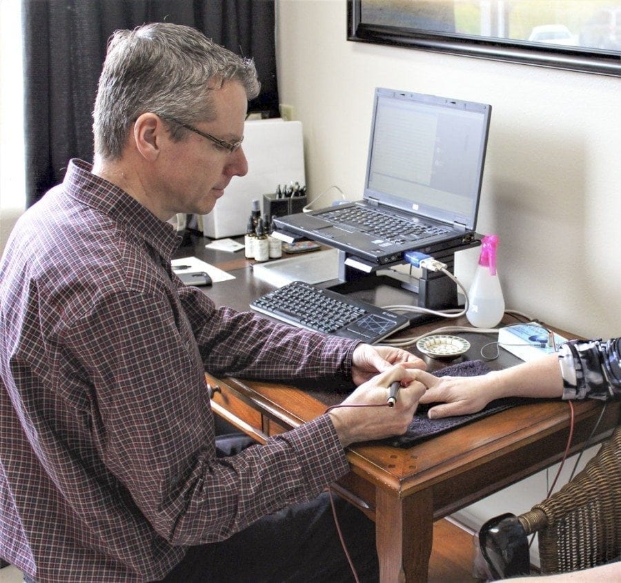 Timothy Lightfoot, an electrodermal screening therapist at Peace Yourself Together, a new holistic healing center located at 506 N.E. Everett St., in Camas, demonstrates the bio-energetic screening equipment he uses at his practice. Photo by Kelly Moyer