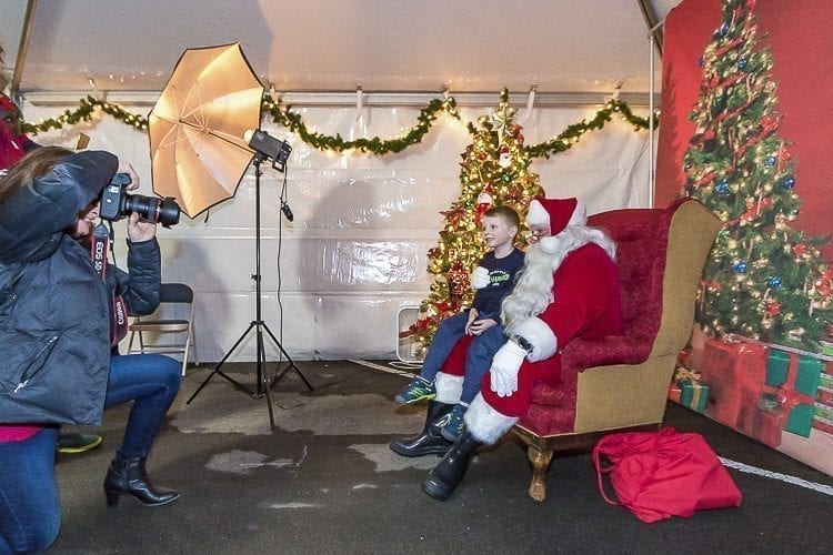 Many families lined up outside of a tent to have their childrens’ pictures taken with Santa Claus during Camas’ Hometown Holidays on Friday. Camas resident Lisa Kuhlman worked as the photographer, and Rick Knapp of Camas appeared as Santa Claus. Here, Harley Kays smiles for the camera and tells Santa what he wants for Christmas. Photo by Mike Schutlz