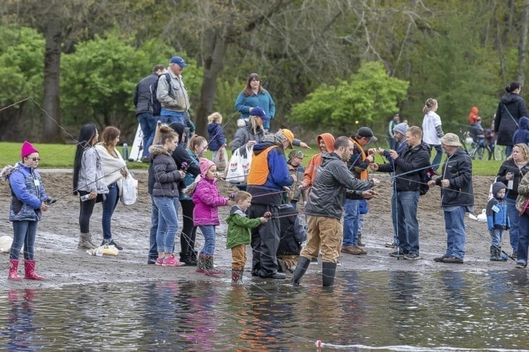 Children, adults and volunteers stand along the beach at Klineline Pond in Salmon Creek Park Saturday morning for the Klineline Kids Fishing Derby. Photo by Mike Schultz
