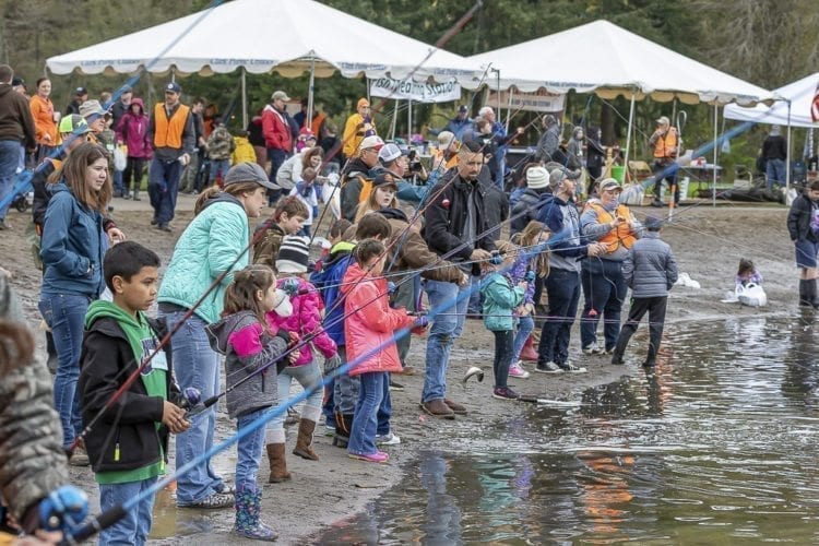 Children, adults and volunteers stand along the beach at Klineline Pond in Salmon Creek Park Saturday morning for the Klineline Kids Fishing Derby. Photo by Mike Schultz