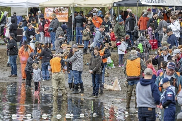 Children, adults and volunteers stand along the beach at Klineline Pond in Salmon Creek Park Saturday morning for the Klineline Kids Fishing Derby. Photo by Mike Schultz