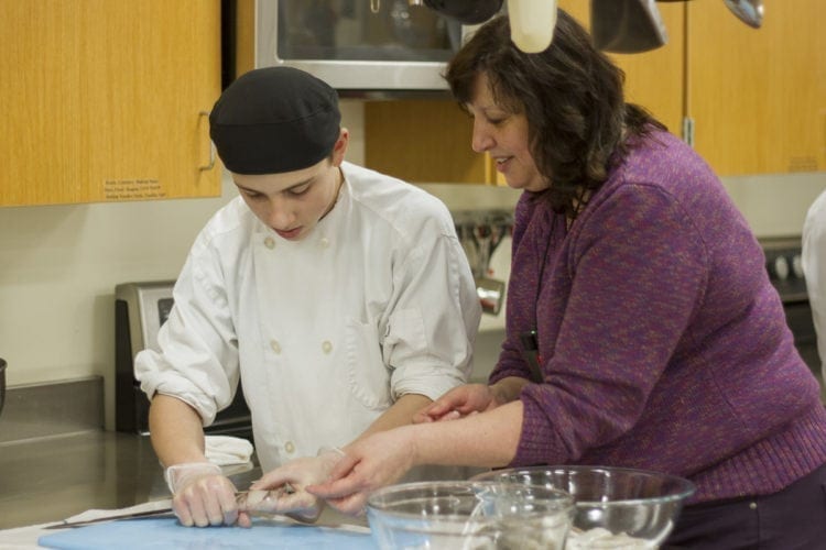 Kimberly Miller helps a Woodland Public Schools’ Culinary Arts student prepare a squid for an upcoming calamari dish. Photo courtesy of Woodland Public Schools