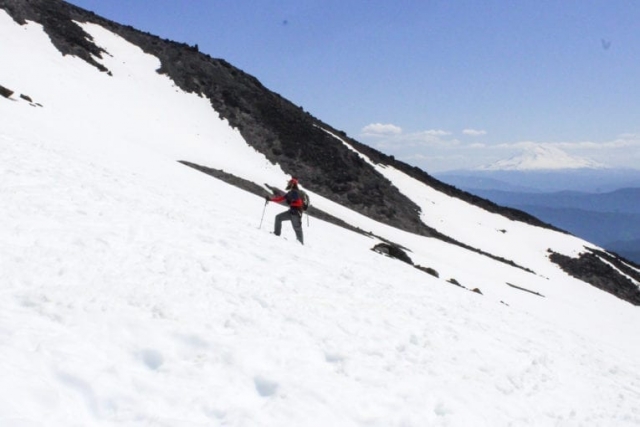 A climber looks toward the summit as Mount Adams looms in the background. Photo by Eric Schwartz