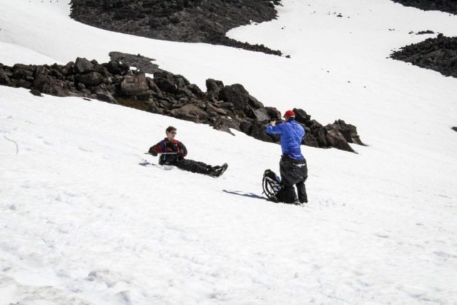 A man photographs a friend glissading down the slopes of Mount St. Helens. Photo by Eric Schwartz
