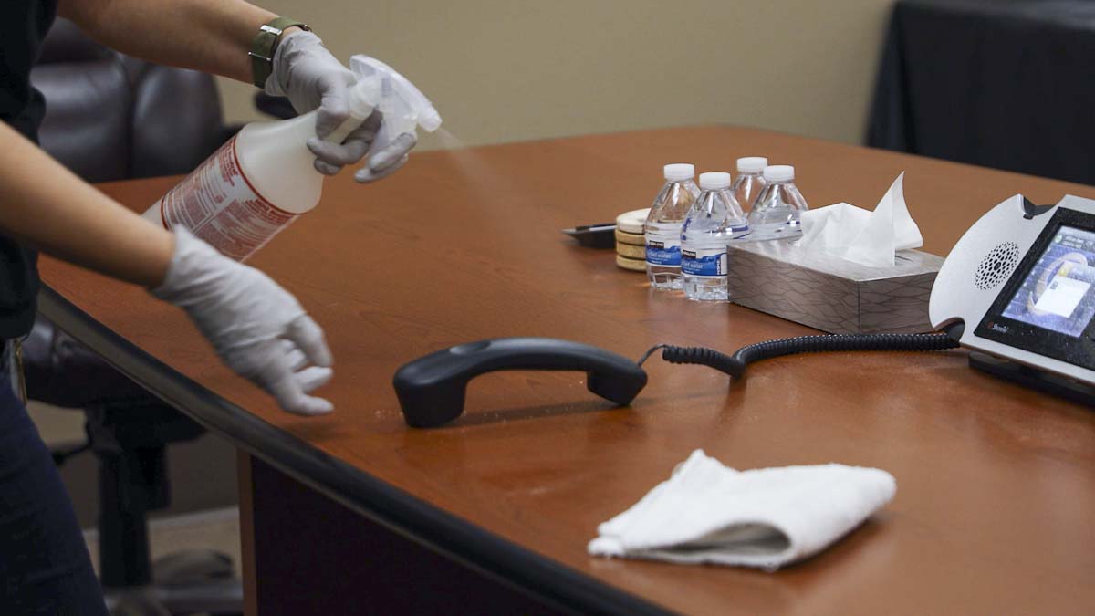 A cleaner sprays disinfectant on a phone inside a conference room at the US Digital Outreach Center in Vancouver. Photo by Jacob Granneman