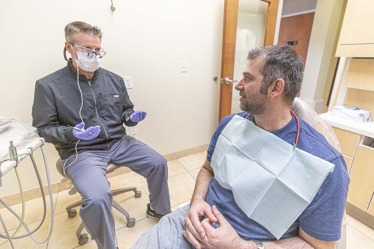 Smiles Dental dentist Dr. Ty Shoemaker is seen here explaining treatment options to urgent patient Dan Stoica. Photo by Mike Schultz