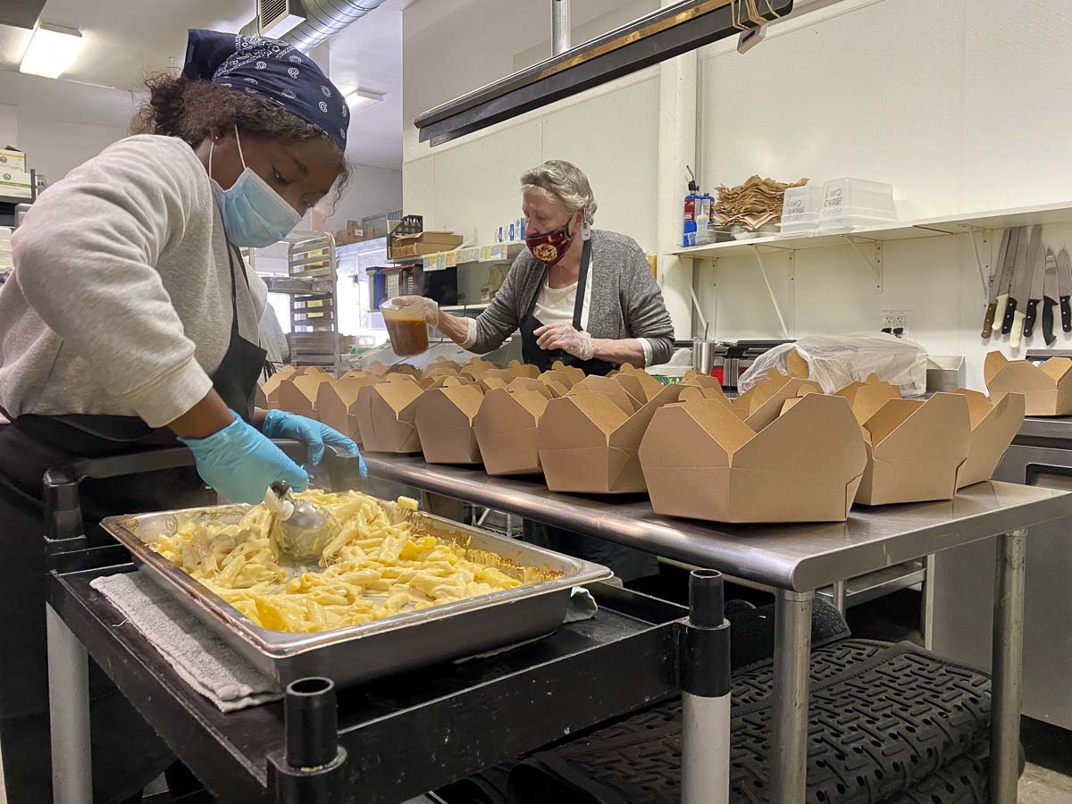 Pearl Muodzi (left) and Sally Cresmer prepare meals for those in need in the Bleu Door Bakery kitchen. The restaurant has been closed since March 19, but volunteers prepared meals for six weeks. Photo by Autumn Stevens of Tink Media