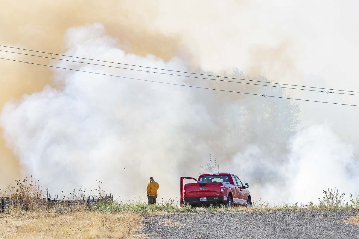 A Vancouver Fire official watches over a grass fire Tuesday along Fruit Valley Road in West Vancouver. Photo by Mike Schultz