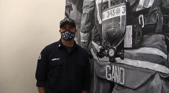 Capt. Clint Greenley stands at the base of his new 15-foot mural in Station 63. Photo courtesy of Fire District 6