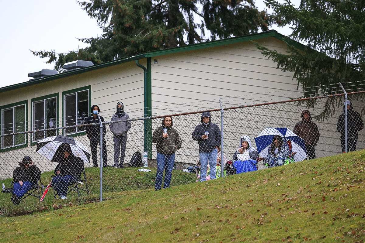 Spectators found a place on the hill, on the outside looking in to McKenzie Stadium at a football game earlier this season. More fans will be allowed in the stadium starting this week. Photo by Mike Schultz