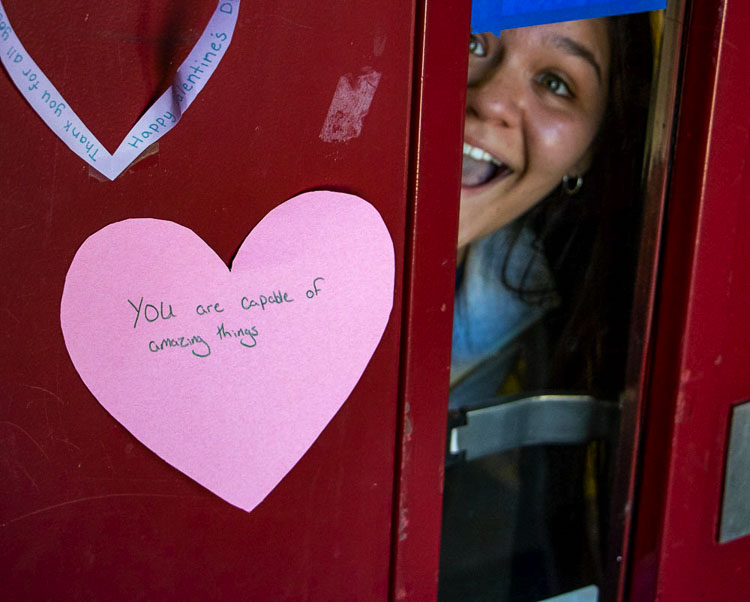 Prairie High School sophomore Soledad Ahumada peeks out from a door holding a heart with an inspirational message. Photo courtesy of Battle Ground Public Schools