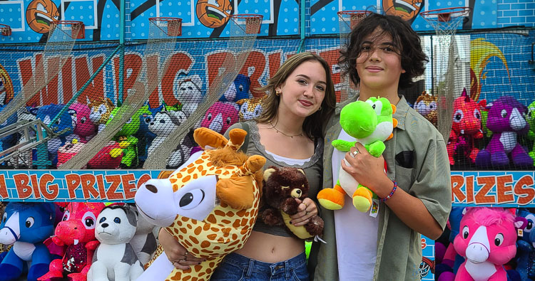 Emily Walker and Robert Cortez show off some of their prizes they won Friday afternoon at the Family Fun Carnival. Cortez won the giraffe, and Walker was grateful. Photo by Paul Valencia