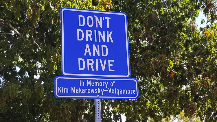 This sign marks the location of the accident and the memory of Kim Makarowsky-Volgamore. The choice of one person to drink and drive killed Kim and forever changed the lives of many others, Photo by John Ley