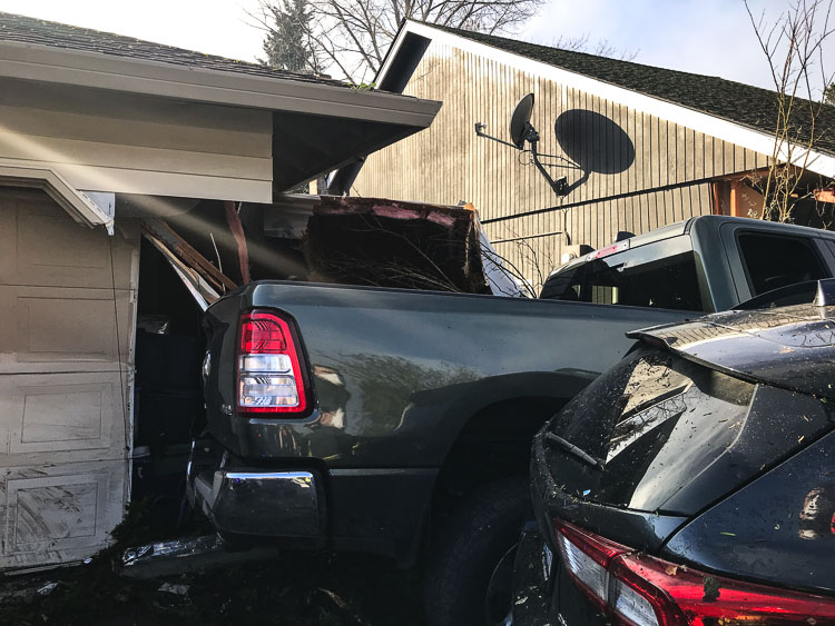 The driver continued through the retaining wall into the next house, colliding with a parked vehicle, moving it out of the driveway. The truck hit the garage door, causing the residence significant damage. Photo courtesy Vancouver Police Department