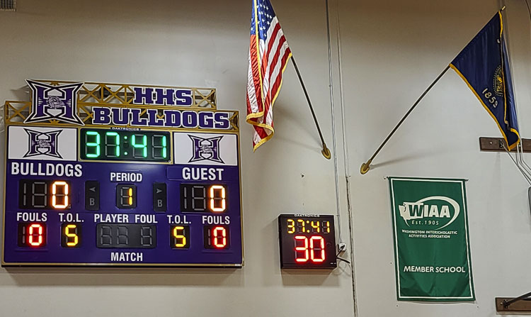 Hermiston High School in Oregon has a shot clock, an Oregon state flag, and a WIAA banner. That’s right. Oregon does not have a shot clock, but Washington schools do. And these days, Hermiston is an Oregon school that competes as a member of the Washington Interscholastic Activities Association. Reporter Paul Valencia had to take in the first Washington state playoff basketball game to be held in Oregon, at a place that remains special in his career, in his heart. Photo by Paul Valencia