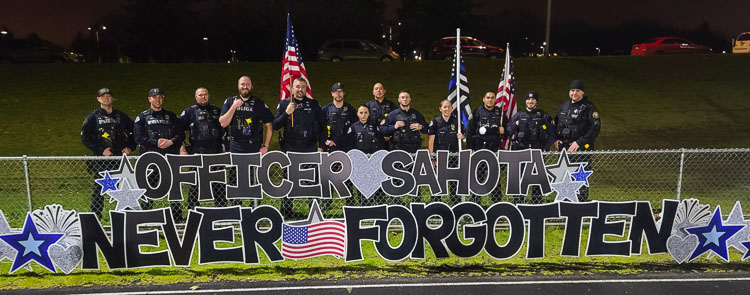 Police officers from Vancouver and Portland who showed up for Friday’s Honor Mile for Vancouver police officer Donald Sahota line up behind a sign for Sahota. Photo by Paul Valencia