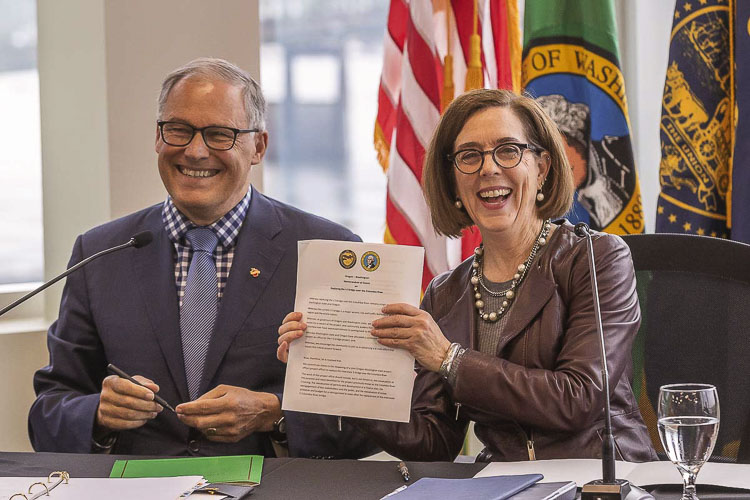 Governors Jay Inslee and Kate Brown signed a memorandum of understanding in Nov. 2019 laying the groundwork for the current Interstate Bridge Replacement Program. It was all smiles and promises of working together at the time. A possible trade and tax war has erupted over Inslee’s support for a tax on refined fuel exported to Oregon and other states. Photo by Mike Schultz