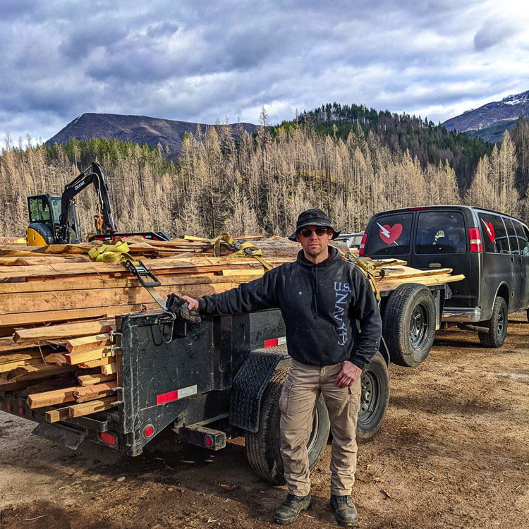 Andrey Ivanov proudly stands next to a trailer load of lumber he and his Spartans have created from burned trees on a Gates, Oregon property. They are helping homeowner Chris Lamb clear the land, create usable lumber, and making money to fund other Spartan Challenge activities. Photo courtesy Andrey Ivanov