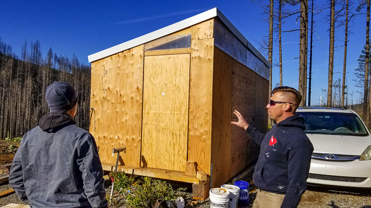 This mini shelter could serve as a homeless shelter or permanent housing for a single mom. Andrey Ivanov shows off the 9x20 structure to Spartan Mark Dubinsky. They have already created a second, larger structure that could house a small family. If Ivanov can continue to access burned trees, he believes he and his Spartan Challenge team could create an ADU compliant living structure for about $35,000 to provide shelter for those less fortunate. Photo by John Ley