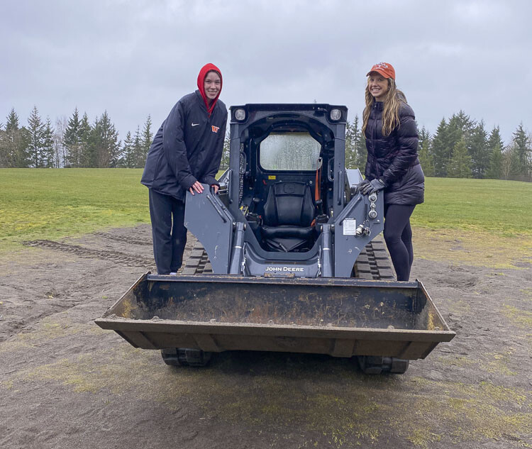 Chloe Asciutto and Emmy Hansen have fun on a skid steer that they used to renovate a beach volleyball court in Camas. Photo courtesy Emmy Hansen