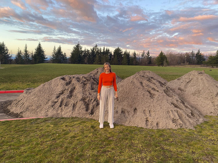 Emmy Hansen stands in front of a pile of sand that was used in the renovation of a beach volleyball court in Camas. Photo courtesy Emmy Hansen