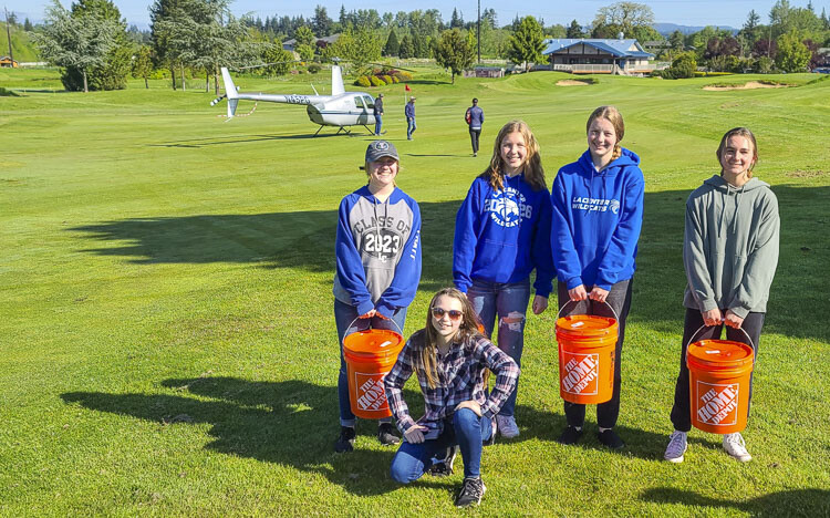 Members of La Center soccer hold the bucket of golf balls to be used on the helicopter for the ball drop fundraiser for the La Center Community Stadium. Photo by Paul Valencia
