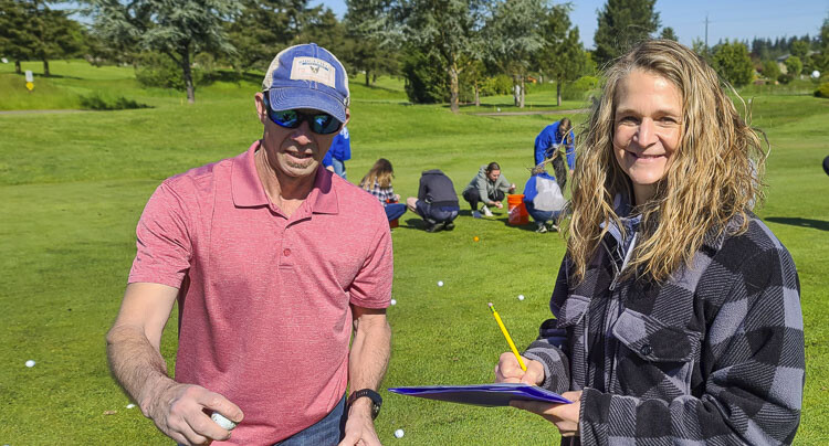 Miriam Bradley, right, is all smiles as she and volunteer Jeff Pratt figure out which golf balls landed closest to the target, to figure out the winners of the ball drop fundraiser on Saturday. Bradley said the event raised $30,000 for the La Center Community Stadium. Photo by Paul Valencia