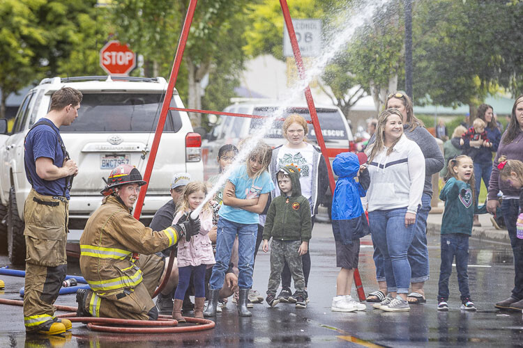 Some attendees got a little wet, thanks to Cowlitz Fire District 1 Captain Justin Huff, who assisted Ella Williams on the nozzle at the Fireman’s Muster. Photo courtesy Mike Schultz