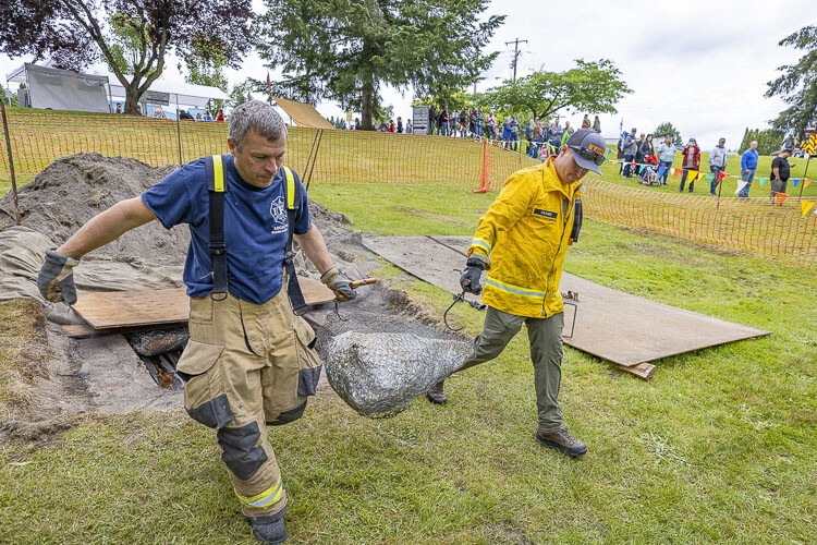 Kevin Saari and Alex Cranke remove the beef from the fire pit for the Fireman’s BBQ. Photo courtesy Mike Schultz