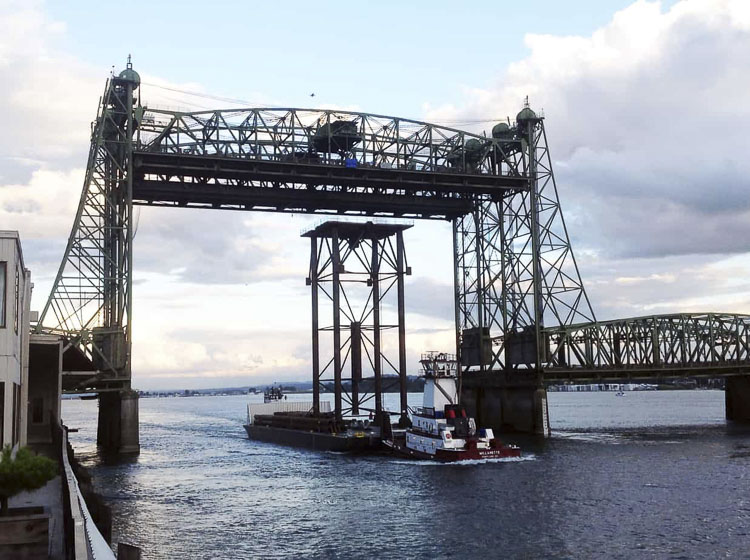 A barge transports a Greenberry project under the Interstate Bridge. Greenberry was offered $25 million in mitigation fees, due to the original Columbia River Crossing proposed bridge being too low to accommodate its needs. Photo courtesy Greenberry Industrial