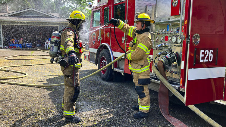 Firefighter Bryson Lemire decontaminates a firefighter after the fire attack. Photo courtesy Clark-Cowlitz Fire Rescue