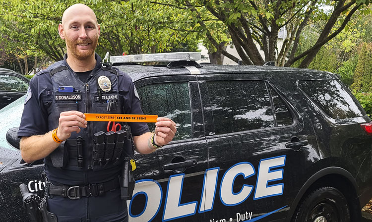 Sean Donaldson of the Vancouver Police Department holds up a Target Zero reflective wrist band that reminds pedestrians to “See and be seen,” important advice prior to Halloween. Photo by Paul Valencia