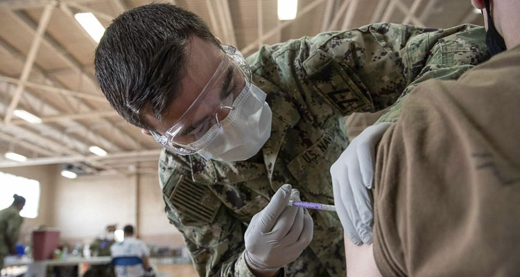 Hospital Corpsman 3rd Class Robert Moore, assigned to U.S.S. George W. Bush medical department, administers a COVID-19 vaccine at the McCormick Gym at Naval Station Norfolk, Va. on April 8, 2021. Photo courtesy Seaman Jackson Adkins/U.S. Navy