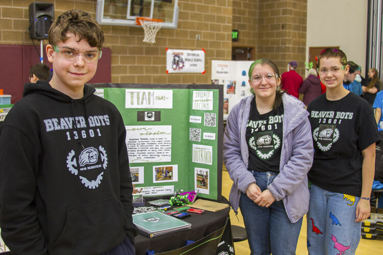 Grayson Tinker (9th), Alyssa VanCleef (11th), and Morrigan Chapman (10th) show the team's informational board used for outreach and recruiting. Photo courtesy Woodland School District