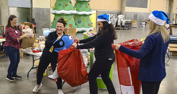 Volunteers filled toys bags, as well as food boxes, for 1,500 families in need, items that will be delivered Sunday morning by Santa’s Posse. Photo by Paul Valencia