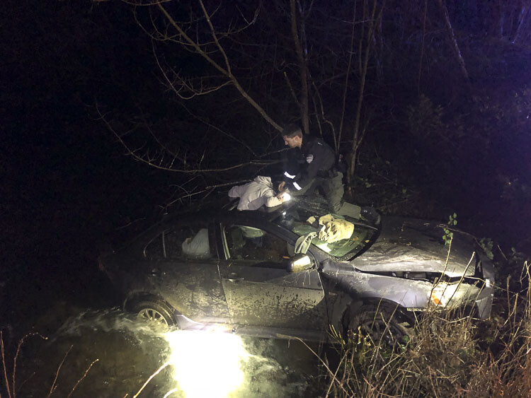 Clark County Sheriff's Deputy Mike Ehrenfelt works to extract the passengers trapped in a vehicle which crashed into Boulder Creek Wednesday night. Photo courtesy Clark County Sheriff’s Office