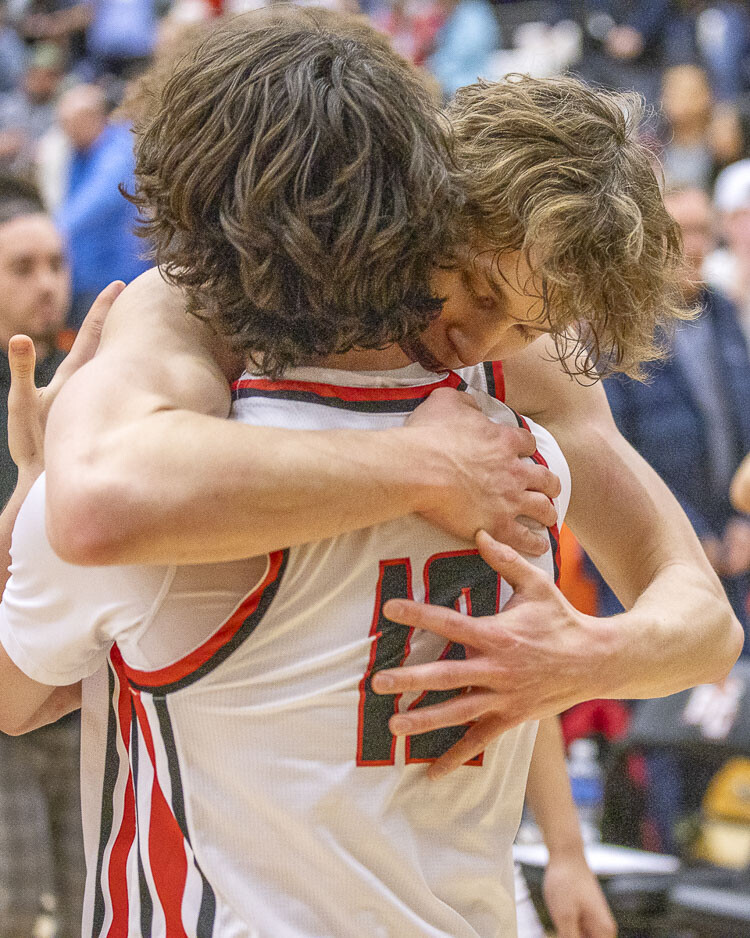 Jace VanVoorhis (12) embraces Josh Dabasinskas as Camas clinched a trip to the Tacoma Dome for the first time in the boys basketball program’s history. Photo by Mike Schultz