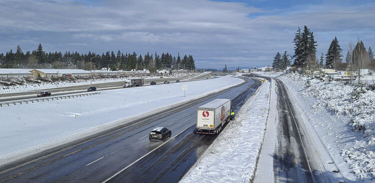 A northbound truck driver on I-205 takes his chains off at around 11 a.m. Thursday. The roads on the freeways are clear of snow but the roads are expected to freeze again overnight as temperatures are forecast to dip into the teens in the region. Photo by Paul Valencia