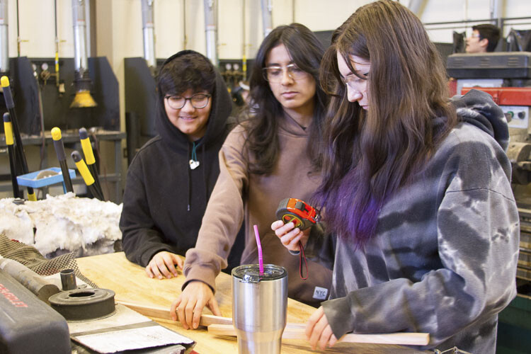 Left to Right: Anahy Juarez, Paula Mora, and Raegen Hanson, all freshmen, measure and cut wood for their project. Photo courtesy Woodland School District