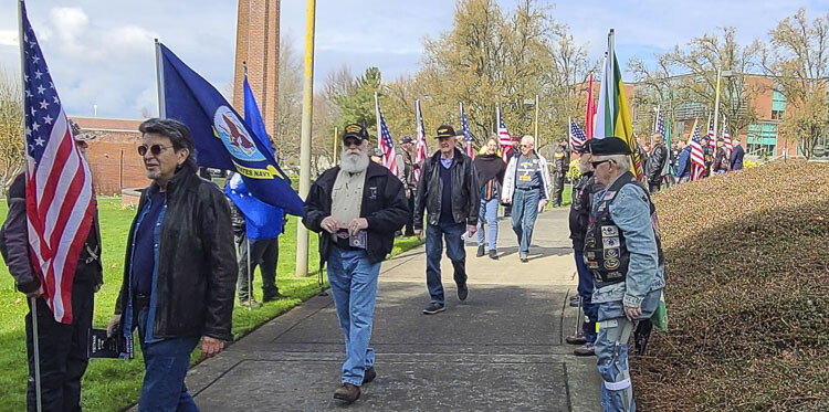 Veterans, family members, and friends walked in between flags held high by the Patriot Guard Riders at a ceremony Wednesday for Vietnam Veterans Day at Clark College. Photo by Paul Valencia