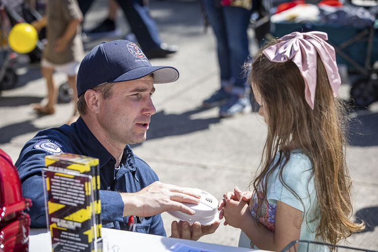 Fire District 3 firefighter Bryan Bosch explains to Charlotte Eslick how smoke detectors work. Photo by Mike Schultz