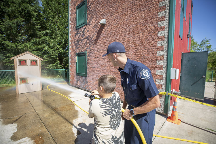 Fire District 3 firefighter Spencer Lieser shows this youngster how to operate a fire hose. Photo by Mike Schultz