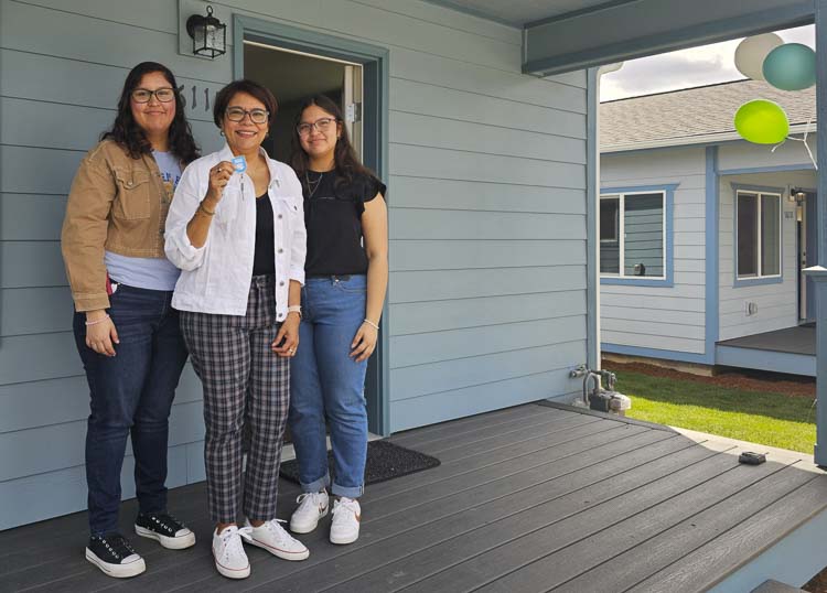 Karla Alvarado Martinez holds up her keys to her new home in Vancouver from Evergreen Habitat for Humanity, celebrating new home ownership with her daughters Clarissa and Maria Elsa. Photo by Paul Valencia