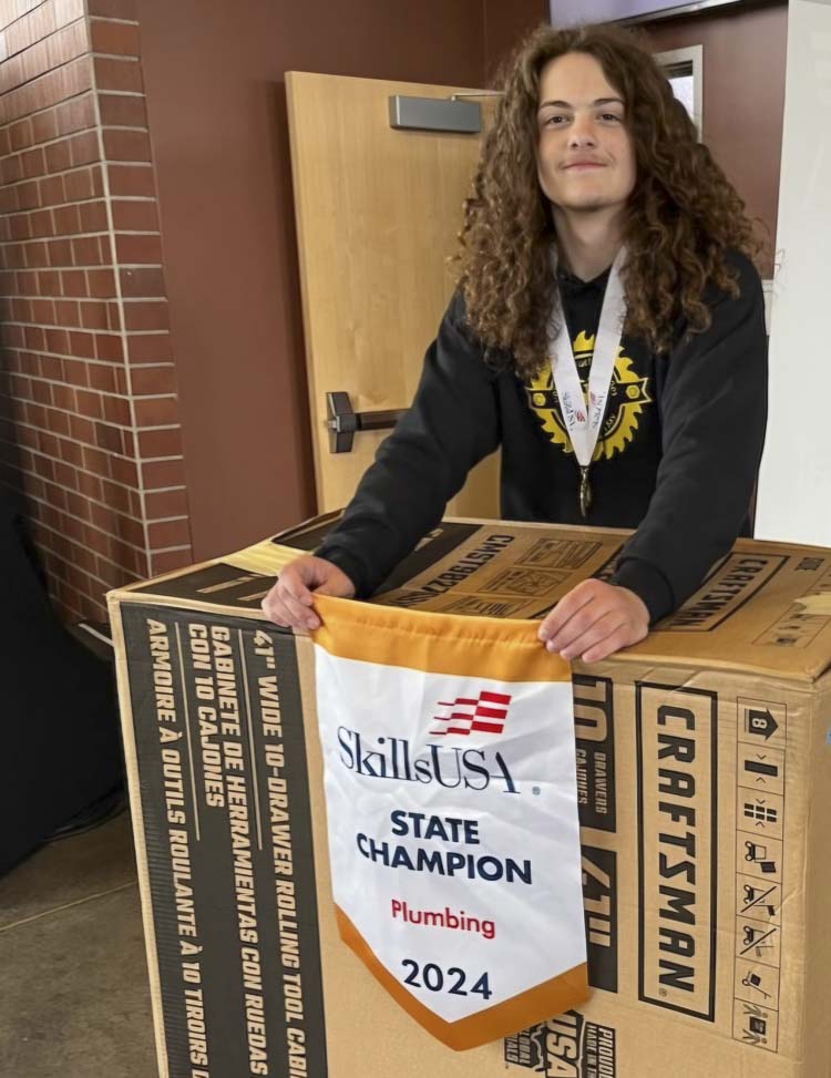 Maxx Van Hoomissen, a senior at Hudson’s Bay High School, stands with his SkillsUSA banner for winning the state championship in plumbing, along with his prize, a rollaway toolbox. Photo courtesy Maxx Van Hoomissen