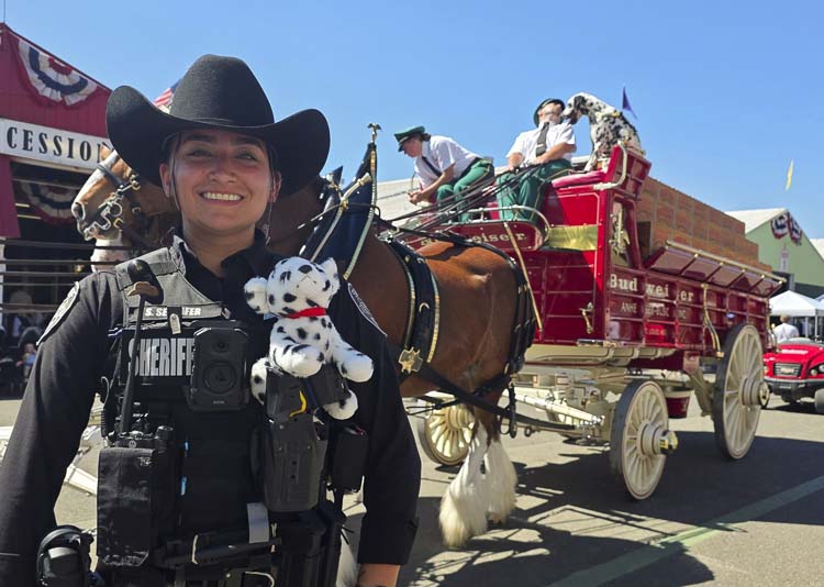 Deputy Sarah Seehafer of the Clark County Sheriff’s Office bought a stuffed Dalmatian, then was able to escort the real thing — King — along with the Clydesdales during Sunday’s parade down the Midway at the Clark County Fair. Photo by Paul Valencia