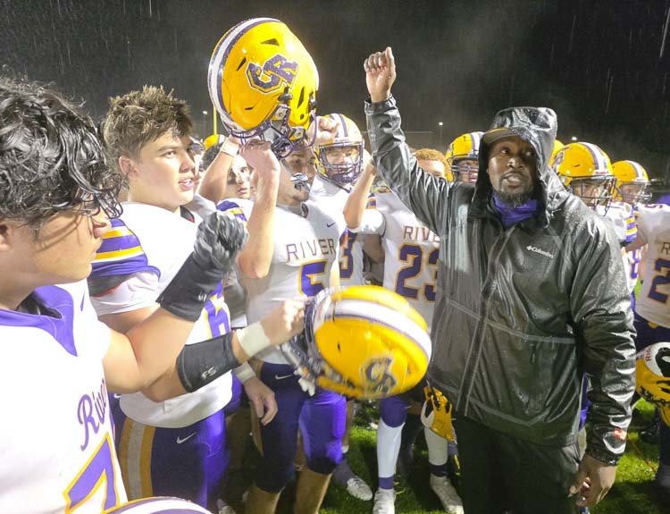 Columbia River coach DeWayne Patterson and the Rapids celebrate in the rain Friday night after beating Hockinson 26-6. Photo by Paul Valencia